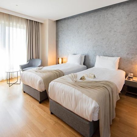 Dosso Dossi Hotels & Spa Downtown Istambul Exterior foto The photo shows a modern hotel room featuring two single beds with white linens and soft gray throw blankets. The room has a stylish design, with wooden flooring and a large window dressed with light curtains that allow natural light to enter. There'
