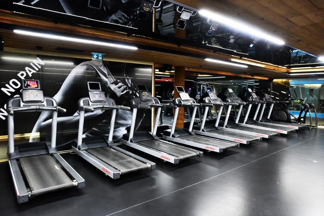 Dosso Dossi Hotels & Spa Downtown Istambul Exterior foto The photo shows a row of treadmills in a gym setting. The treadmills are modern and aligned next to each other on a sleek black floor. The background features a large image of a runner's foot, with motivational phrases that suggest themes of fitness 
