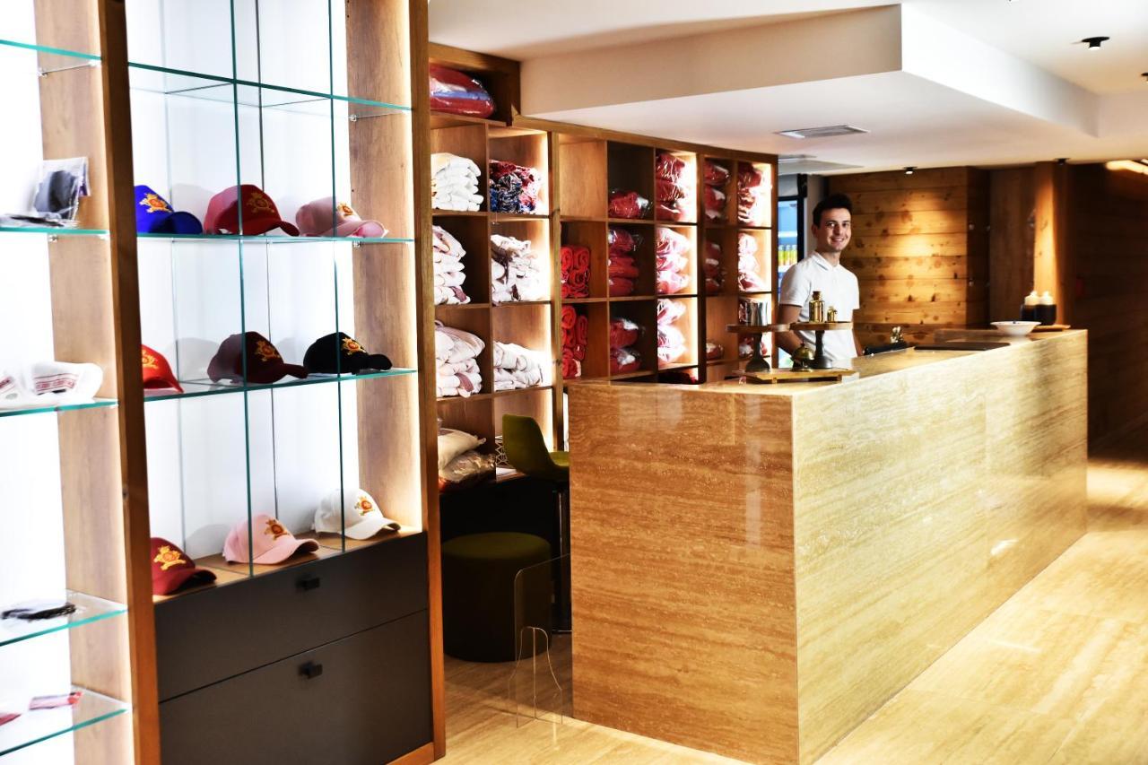 Dosso Dossi Hotels & Spa Downtown Istambul Exterior foto The photo shows a retail space or reception area with a warm and modern design. On the left, there are shelves displaying various colorful caps, neatly arranged behind glass. The right side features a wooden counter where a staff member is standing, 