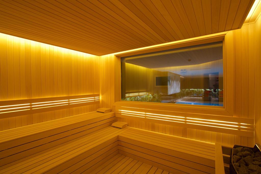 Dosso Dossi Hotels & Spa Downtown Istambul Exterior foto The photo depicts a sauna interior characterized by wooden paneling and warm, ambient lighting. The walls and seating are made of light-colored wood, creating a cozy atmosphere. There is a large window that offers a view into another room, possibly f