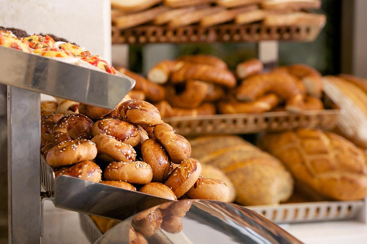 Dosso Dossi Hotels & Spa Downtown Istambul Exterior foto The photo shows a display of various types of baked goods. In the foreground, there are small, round bread rolls topped with sesame seeds. Behind them, multiple trays are stacked with an assortment of different breads, including twisted rolls and loa