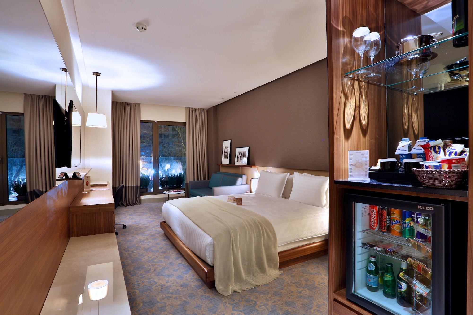Dosso Dossi Hotels & Spa Downtown Istambul Exterior foto The photo shows a well-decorated hotel room featuring a large bed with white linens, a bedside table, and modern furnishings. There are two windows with curtains that allow natural light to enter the space, and the walls are painted in warm, neutral 