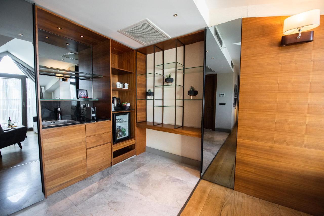 Dosso Dossi Hotels & Spa Downtown Istambul Exterior foto The photo shows a modern interior space that features a blend of wood and glass elements. On the left side, there is a kitchenette area with wooden cabinetry and a small refrigerator, while the right side showcases a glass display unit with shelves f