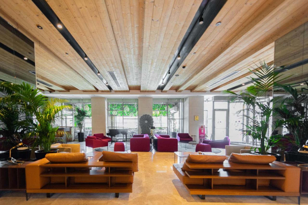Dosso Dossi Hotels & Spa Downtown Istambul Exterior foto The photo shows a modern and spacious lobby area. There are wooden beams on the ceiling, giving the space a warm and inviting atmosphere. The flooring appears to be light-colored stone or tile. 

In the center of the room, there are several seating a