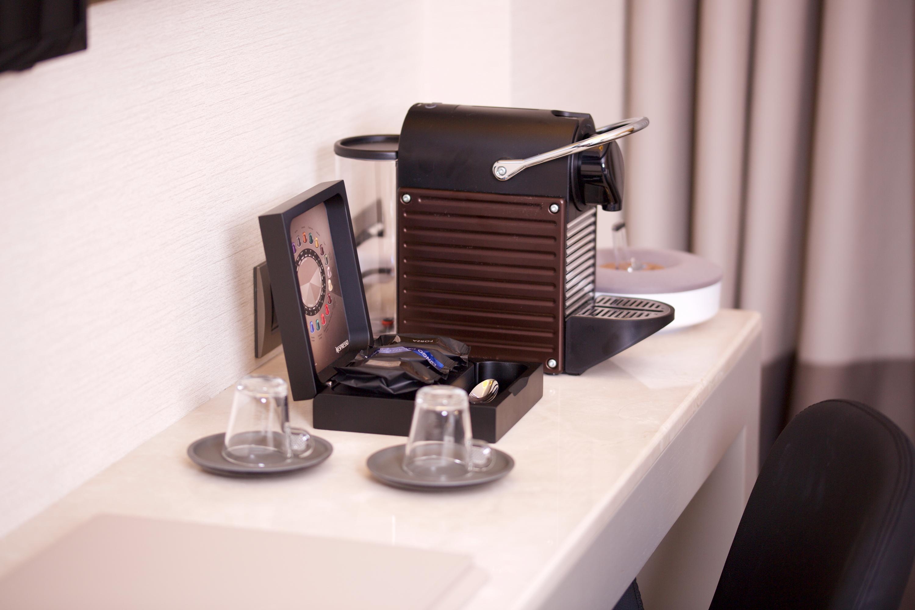 Dosso Dossi Hotels & Spa Downtown Istambul Exterior foto The photo shows a coffee machine placed on a light-colored countertop. The machine appears to be a Nespresso-style espresso maker, featuring a sleek, modern design in black. Next to the machine, there is a small decorative box containing coffee pods.