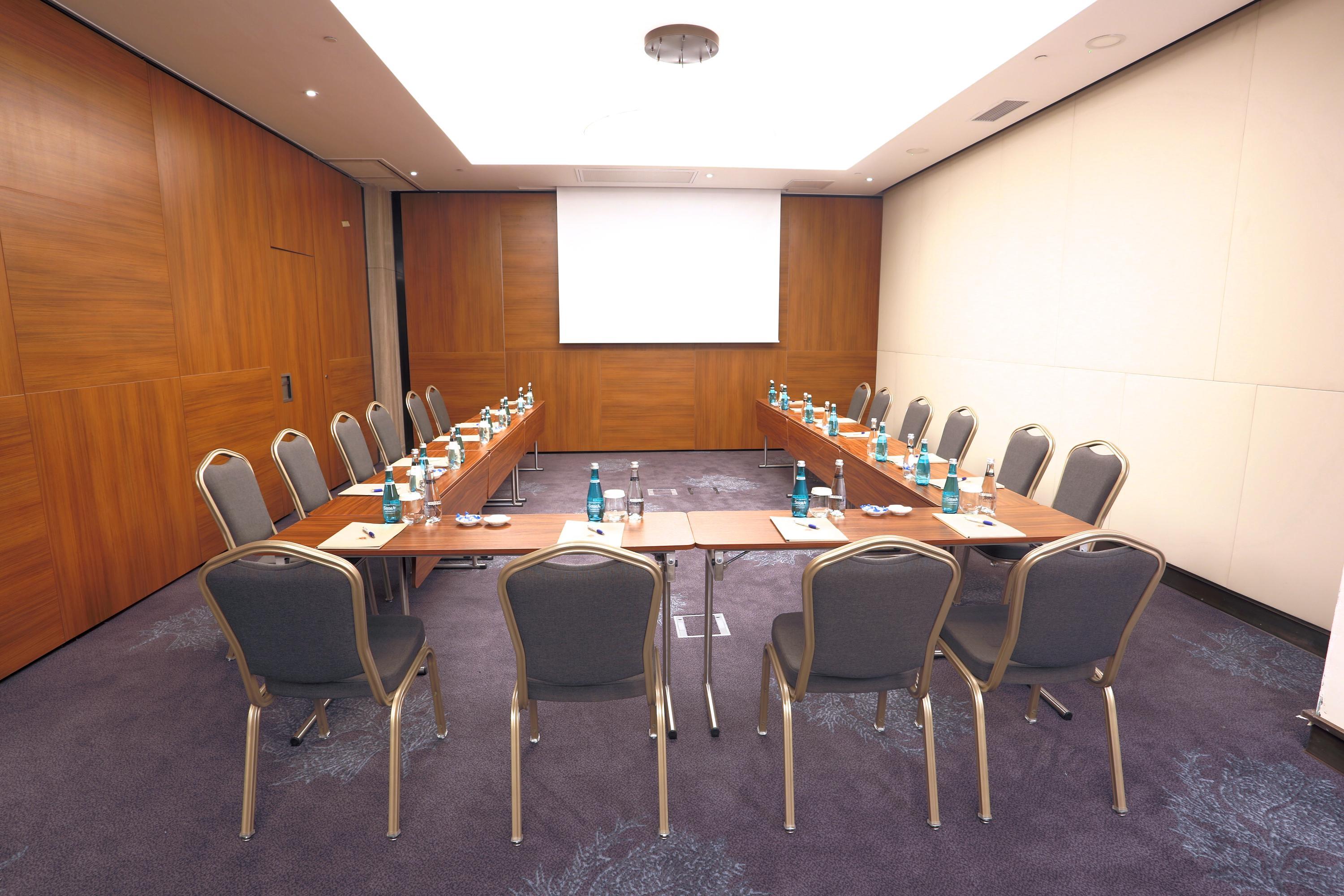 Dosso Dossi Hotels & Spa Downtown Istambul Exterior foto The photo shows a conference room setup. There are several rectangular tables arranged in a U-shape, surrounded by chairs. Each table has a water bottle and a notepad placed on it, suggesting it's intended for a meeting or presentation. The walls are