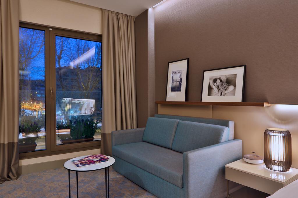 Dosso Dossi Hotels & Spa Downtown Istambul Exterior foto The photo shows a modern and cozy interior of a room. There is a light blue sofa positioned against a wall, accompanied by a round coffee table with a magazine on top. Two black-and-white framed photographs are hanging on the wall above the sofa. Lar