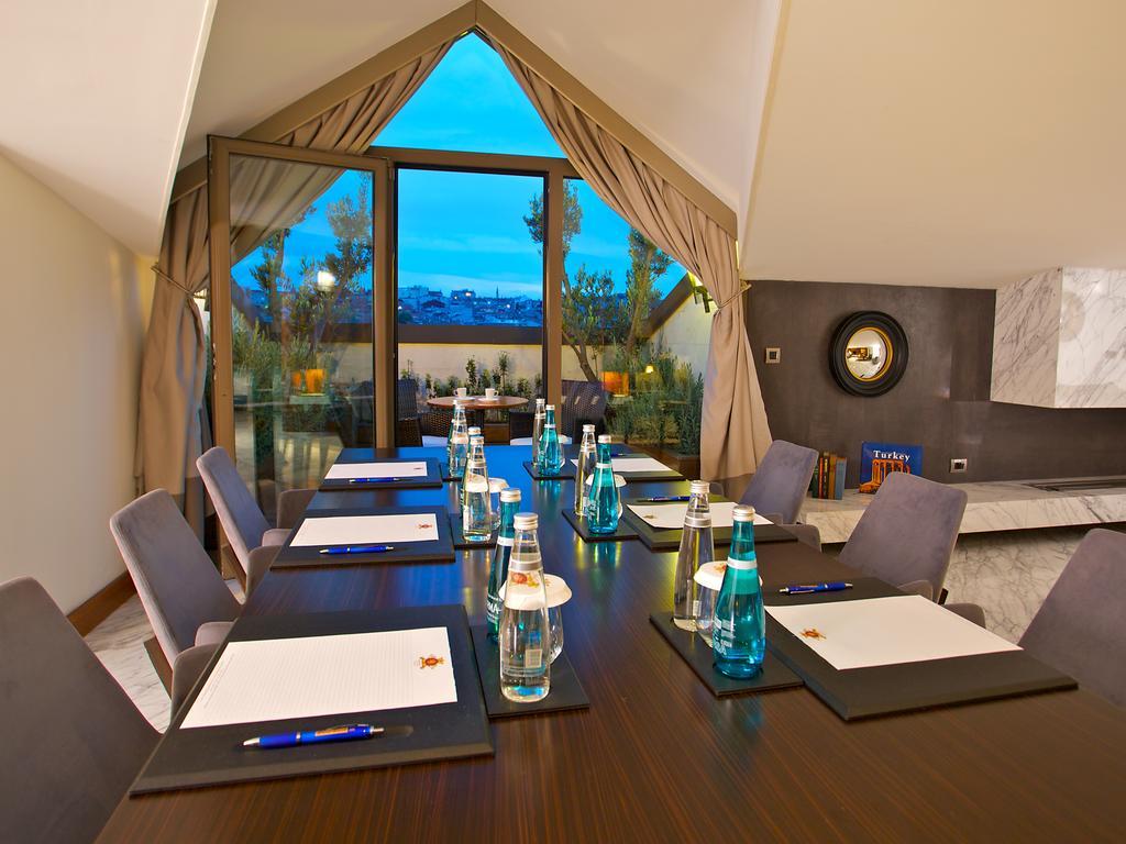 Dosso Dossi Hotels & Spa Downtown Istambul Exterior foto The photo shows a conference room setup. There is a long wooden table with several chairs arranged around it. On the table, there are notebooks or notepads, pens, and bottles of water, all placed neatly. The room features large windows with curtains,