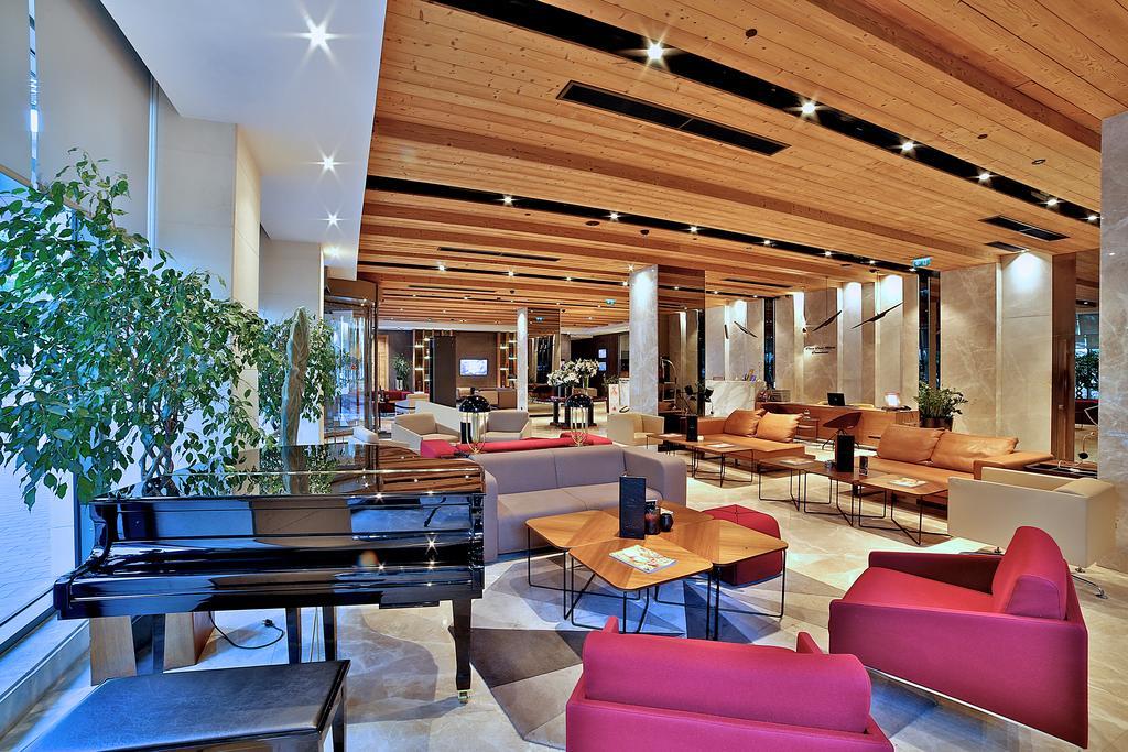 Dosso Dossi Hotels & Spa Downtown Istambul Exterior foto The image shows a spacious and modern lobby area of a building, likely a hotel or an upscale public space. The interior features a high wooden ceiling with ambient lighting, giving it a warm and inviting atmosphere. 

In the foreground, there is a gr